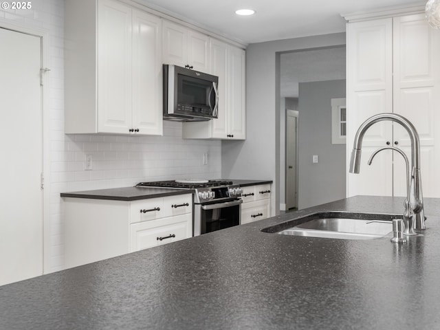 13145 SW 61st Ave, Portland, OR 97219 - kitchen with gas stove, dark countertops, a sink, white cabinets, and decorative backsplash