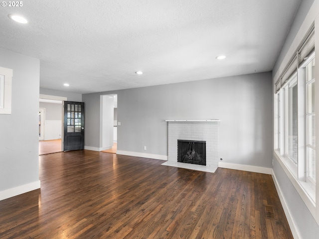 13145 SW 61st Ave, Portland, OR 97219 - unfurnished living room featuring wood finished floors, a brick fireplace, recessed lighting, a textured ceiling, and baseboards
