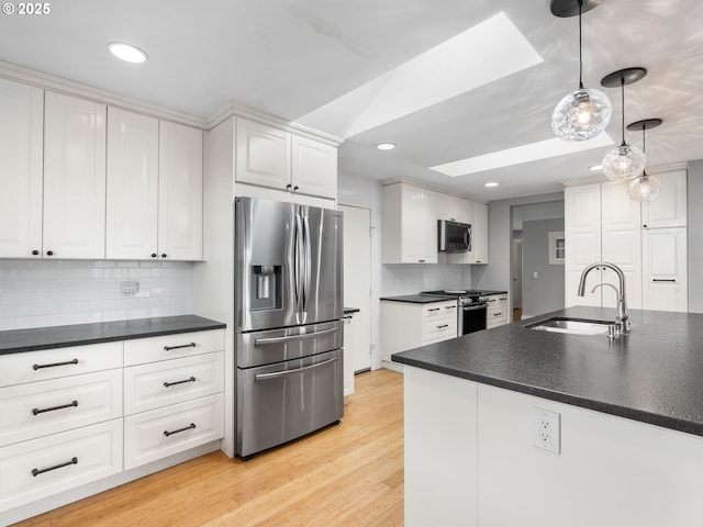 13145 SW 61st Ave, Portland, OR 97219 - kitchen featuring appliances with stainless steel finishes, a sink, a skylight, dark countertops, and recessed lighting