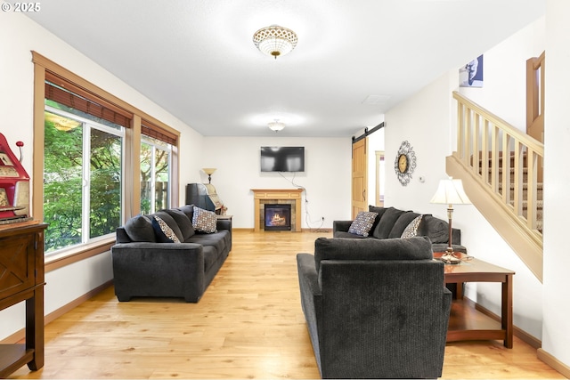 403 W Oxford St, Newberg, OR 97132 - living room featuring light wood-type flooring, a barn door, stairway, baseboards, and a glass covered fireplace