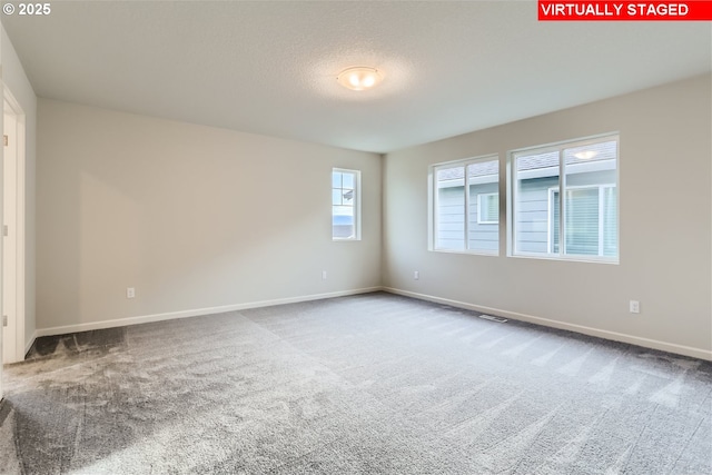 unfurnished room featuring visible vents, carpet flooring, a textured ceiling, and baseboards