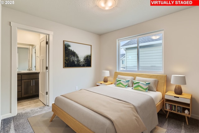 bedroom with a textured ceiling, baseboards, connected bathroom, and light colored carpet