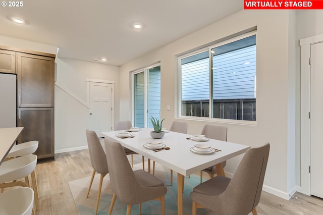 dining space featuring baseboards, light wood finished floors, and recessed lighting