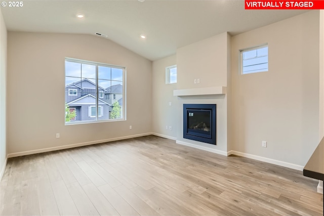 unfurnished living room with lofted ceiling, recessed lighting, wood finished floors, baseboards, and a glass covered fireplace