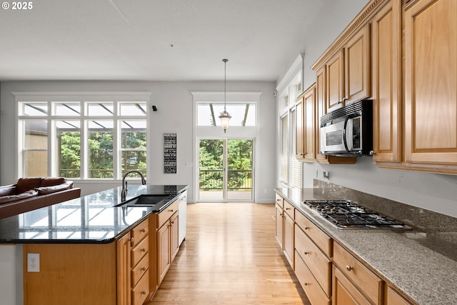 15110 Oyer Dr, Oregon City, OR 97045 - kitchen featuring appliances with stainless steel finishes, light wood-style floors, dark stone counters, a kitchen island with sink, and pendant lighting