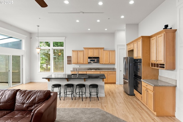 15110 Oyer Dr, Oregon City, OR 97045 - kitchen with appliances with stainless steel finishes, open floor plan, a breakfast bar area, light wood finished floors, and recessed lighting
