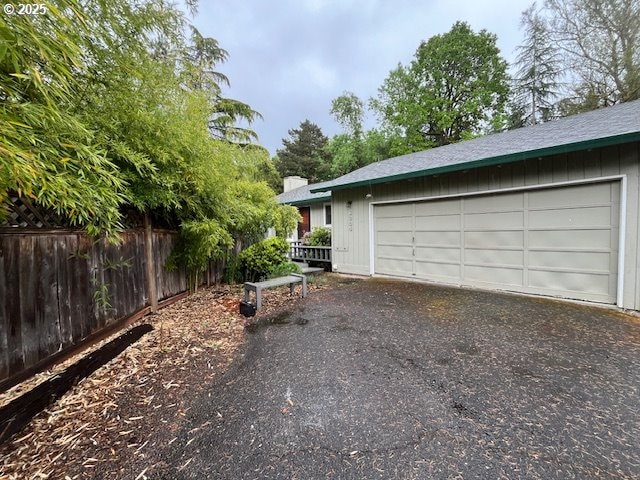 garage featuring driveway and fence