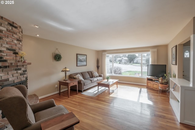 living room featuring light wood-style floors, a fireplace, and baseboards