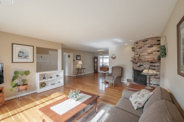 living room with light wood finished floors, a fireplace, and baseboards