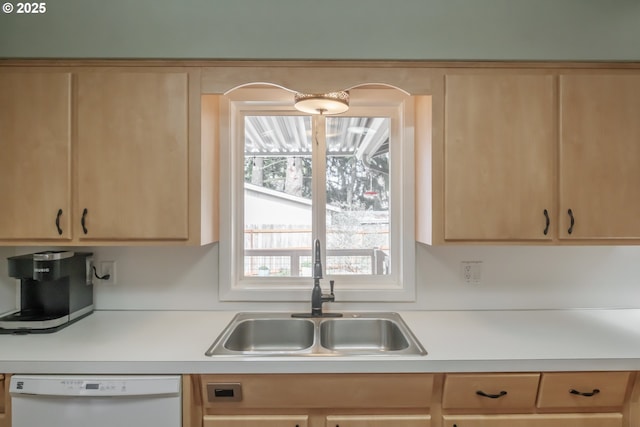 kitchen with light brown cabinets, white dishwasher, light countertops, and a sink