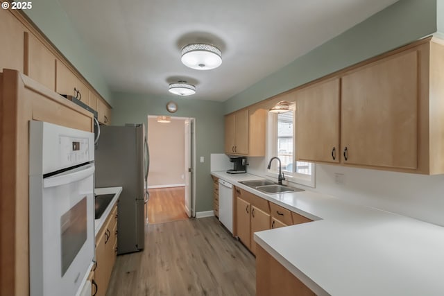 kitchen featuring white appliances, light countertops, light wood-type flooring, light brown cabinets, and a sink