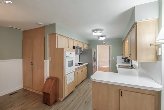 kitchen featuring light brown cabinets, a sink, visible vents, appliances with stainless steel finishes, and light wood-type flooring