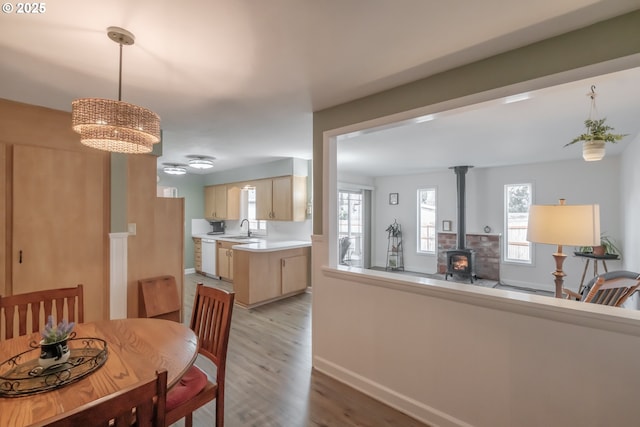 dining space with a wood stove, light wood-style flooring, and baseboards