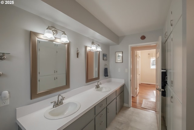 bathroom with a sink, baseboards, and double vanity