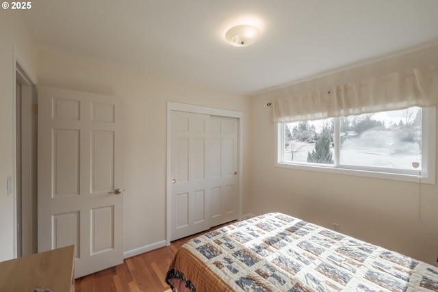 bedroom with a closet, baseboards, and wood finished floors