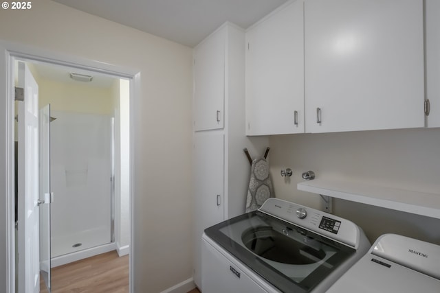 clothes washing area featuring baseboards, independent washer and dryer, cabinet space, and light wood-style floors