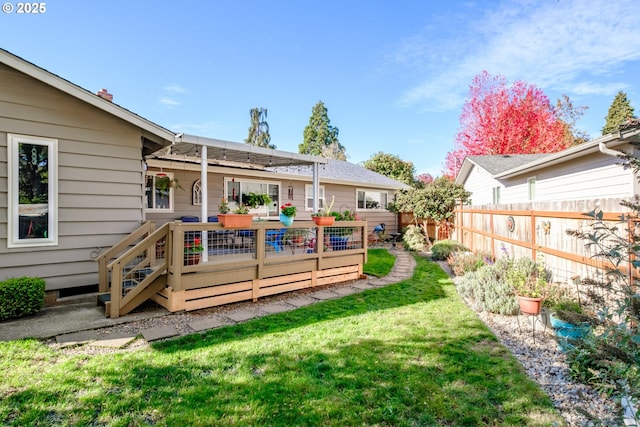 rear view of property with a deck, a yard, and fence