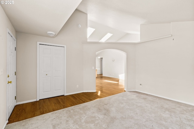 2494 Cubit St, Eugene, OR 97402 - unfurnished bedroom featuring carpet, arched walkways, baseboards, wood finished floors, and a skylight