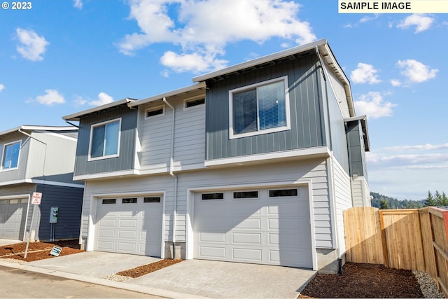 view of front facade with fence, an attached garage, and driveway