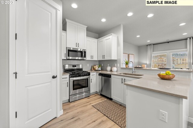 kitchen featuring stainless steel appliances, a sink, recessed lighting, backsplash, and light wood-type flooring