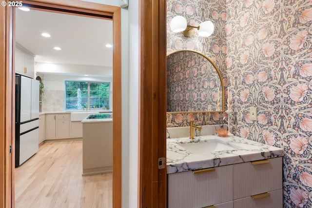 bathroom with vanity, recessed lighting, wood finished floors, and wallpapered walls