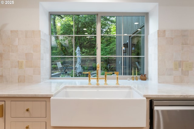 interior space featuring stainless steel dishwasher, a sink, backsplash, and light stone counters