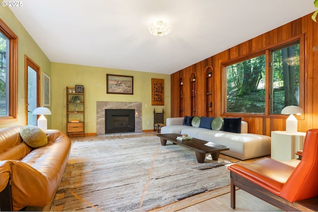 living room featuring wooden walls, wood finished floors, and a high end fireplace