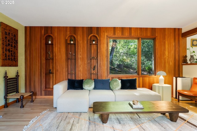 living area with baseboards, wood walls, and wood finished floors