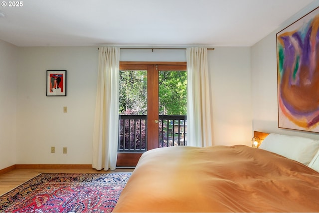 bedroom featuring baseboards, wood finished floors, and access to exterior