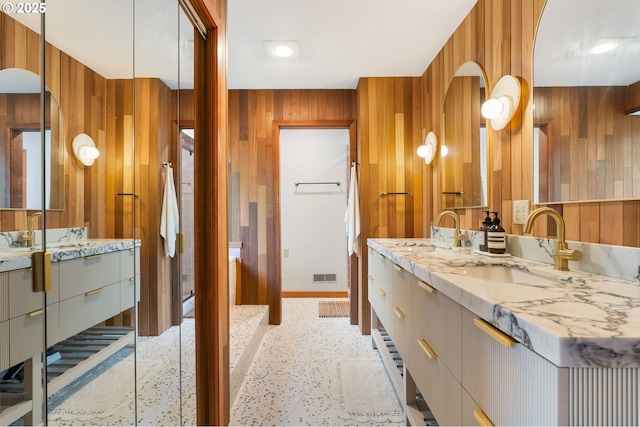 bathroom with vanity, baseboards, wood walls, and visible vents
