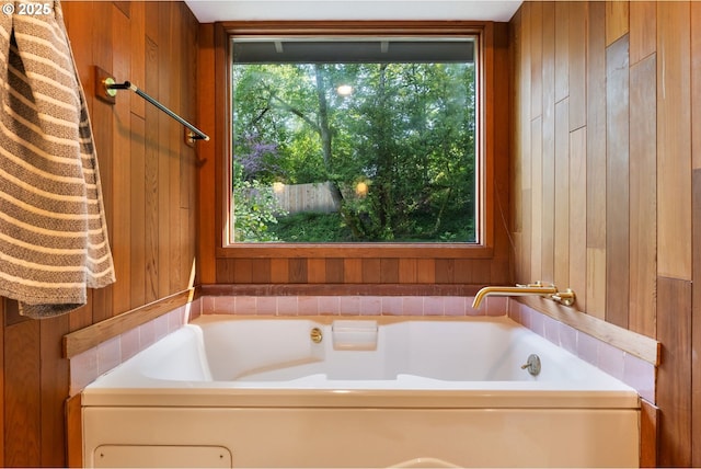 bathroom featuring a garden tub and wooden walls