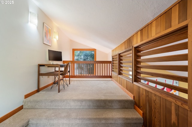 staircase featuring carpet floors, baseboards, and lofted ceiling