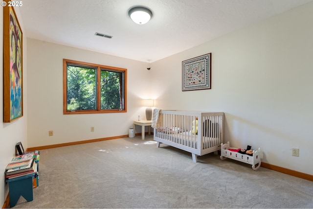 carpeted bedroom with visible vents, baseboards, and a crib