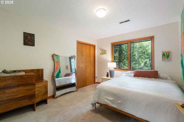 bedroom with light colored carpet, visible vents, and a closet