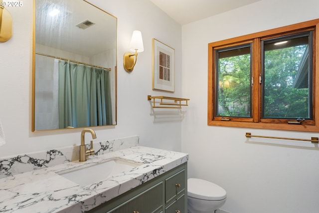 full bathroom with vanity, a shower with shower curtain, toilet, and visible vents