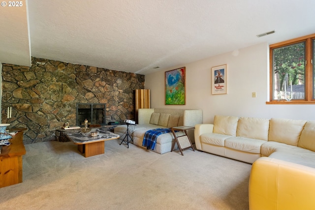 living area featuring carpet floors, a stone fireplace, a textured ceiling, and visible vents
