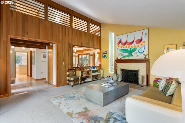 carpeted living area with wood walls, a fireplace with flush hearth, and vaulted ceiling