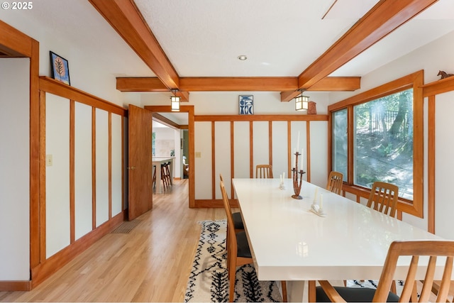 interior space with baseboards, beamed ceiling, and light wood finished floors