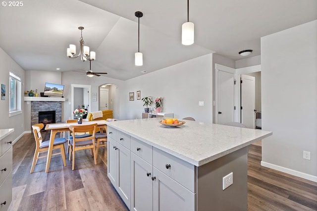 902 SE 3rd St, Prineville, OR 97754 - kitchen featuring wood finished floors, a center island, a stone fireplace, arched walkways, and open floor plan