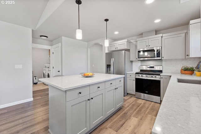 902 SE 3rd St, Prineville, OR 97754 - kitchen featuring separate washer and dryer, light wood-style flooring, decorative backsplash, appliances with stainless steel finishes, and a sink
