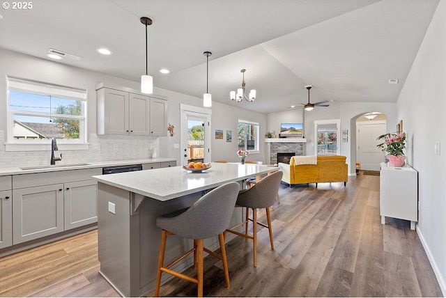 902 SE 3rd St, Prineville, OR 97754 - kitchen featuring a sink, a kitchen island, light wood-type flooring, a stone fireplace, and ceiling fan with notable chandelier