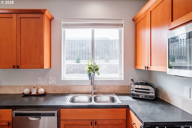 kitchen with a sink, dark countertops, and dishwasher
