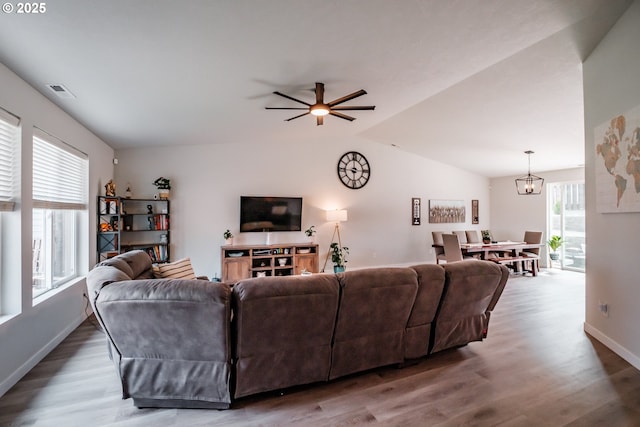 living room featuring lofted ceiling, baseboards, visible vents, and wood finished floors