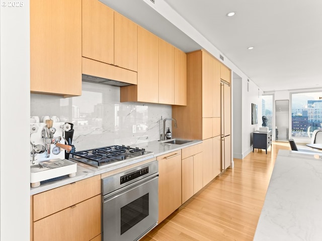 kitchen featuring light brown cabinetry, tasteful backsplash, sink, stainless steel appliances, and light hardwood / wood-style flooring