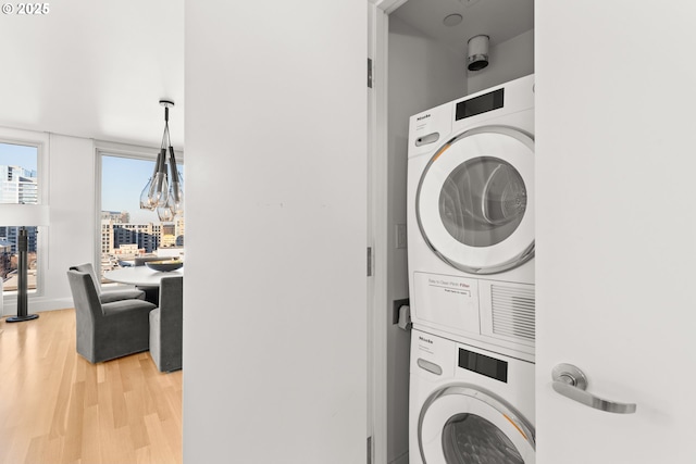 clothes washing area with stacked washing maching and dryer and light hardwood / wood-style floors