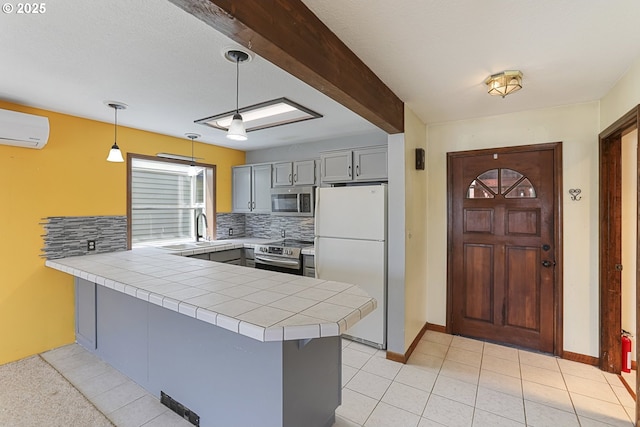 26400 NW St Helens Rd Unit 57, Scappoose, OR 97056 - kitchen with appliances with stainless steel finishes, a peninsula, decorative backsplash, gray cabinetry, and a wall mounted air conditioner