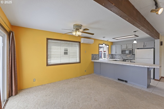 26400 NW St Helens Rd Unit 57, Scappoose, OR 97056 - kitchen with a wall mounted air conditioner, a peninsula, stainless steel microwave, gray cabinets, and light carpet