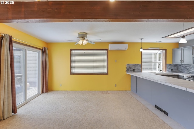 26400 NW St Helens Rd Unit 57, Scappoose, OR 97056 - kitchen with a wall unit AC, tile countertops, a sink, gray cabinetry, and light carpet