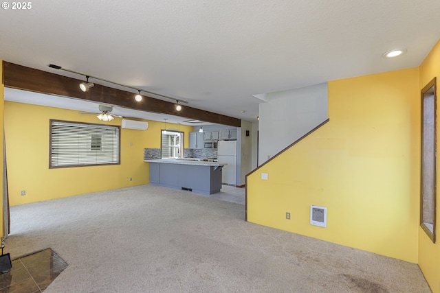 26400 NW St Helens Rd Unit 57, Scappoose, OR 97056 - unfurnished living room featuring light carpet, a wall unit AC, rail lighting, and ceiling fan