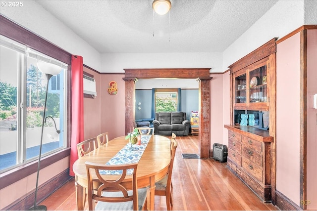 8014 N Johnswood Dr, Portland, OR 97203 - dining space featuring light wood-type flooring, a textured ceiling, and a wall unit AC